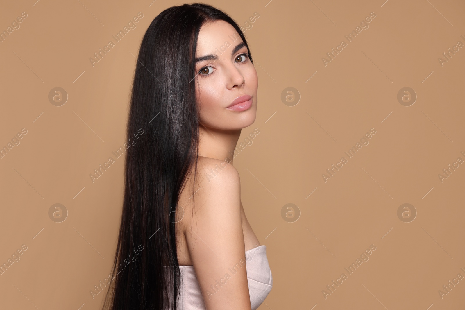 Photo of Portrait of beautiful young woman with healthy strong hair on beige background