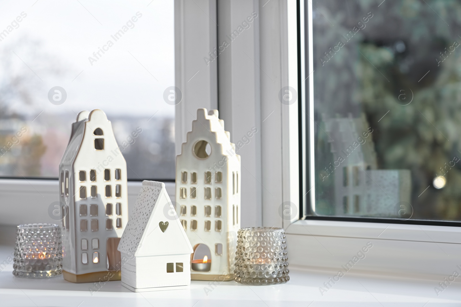 Photo of Beautiful house shaped candle holders on windowsill indoors, space for text