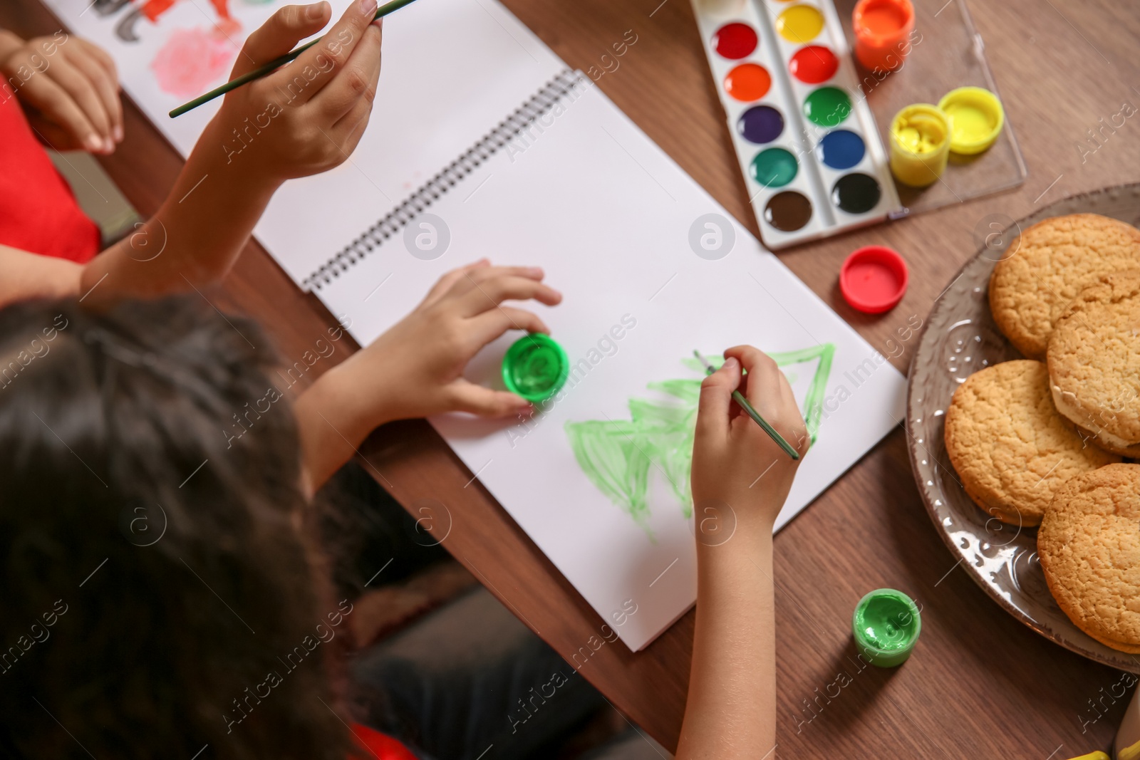 Photo of Little child painting picture at home. Christmas celebration