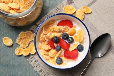 Photo of Delicious crispy cornflakes with milk and fresh berries on light blue wooden table, flat lay