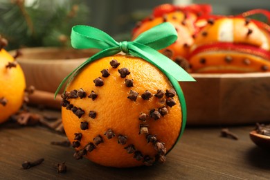 Photo of Pomander ball with green ribbon made of fresh tangerine and cloves on wooden table