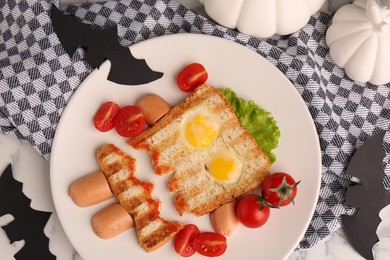 Photo of Cute monster sandwich with cherry tomatoes, fried eggs and sausages on white marble table, flat lay. Halloween snack