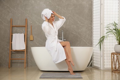 Beautiful woman sitting on edge of tub in bathroom