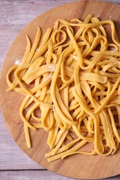 Board with homemade pasta on wooden table, top view