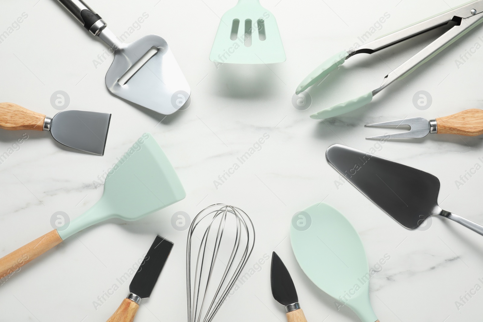 Photo of Frame of different spatulas and other kitchen utensils on light marble table, flat lay. Space for text