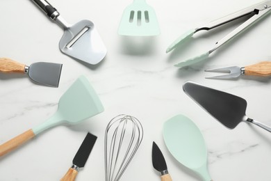 Photo of Frame of different spatulas and other kitchen utensils on light marble table, flat lay. Space for text