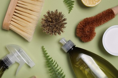 Flat lay composition with different cleaning supplies on green background