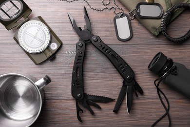 Flat lay composition with compact portable multitool and accessories on wooden table