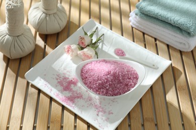 Photo of Bowl of pink sea salt and beautiful roses on wooden table