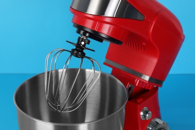 Photo of Closeup view of modern red stand mixer on turquoise background