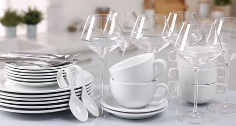 Photo of Set of clean dishware, glasses and cutlery on table in kitchen