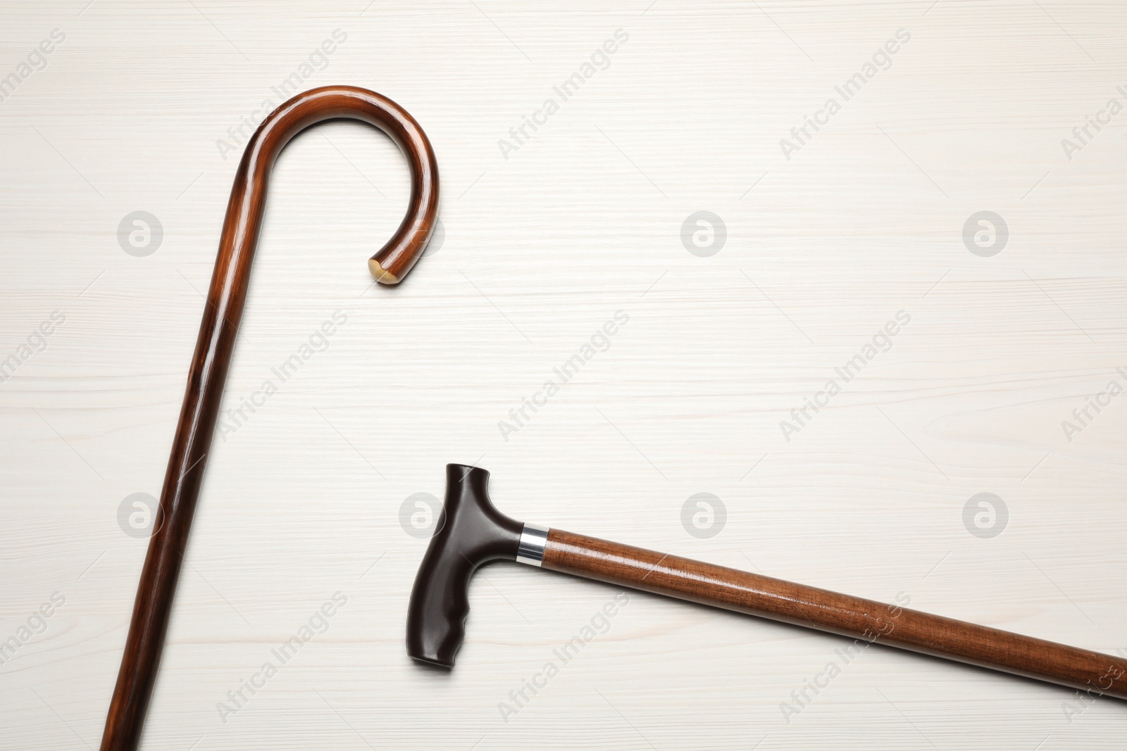 Photo of Walking canes on white wooden background, flat lay