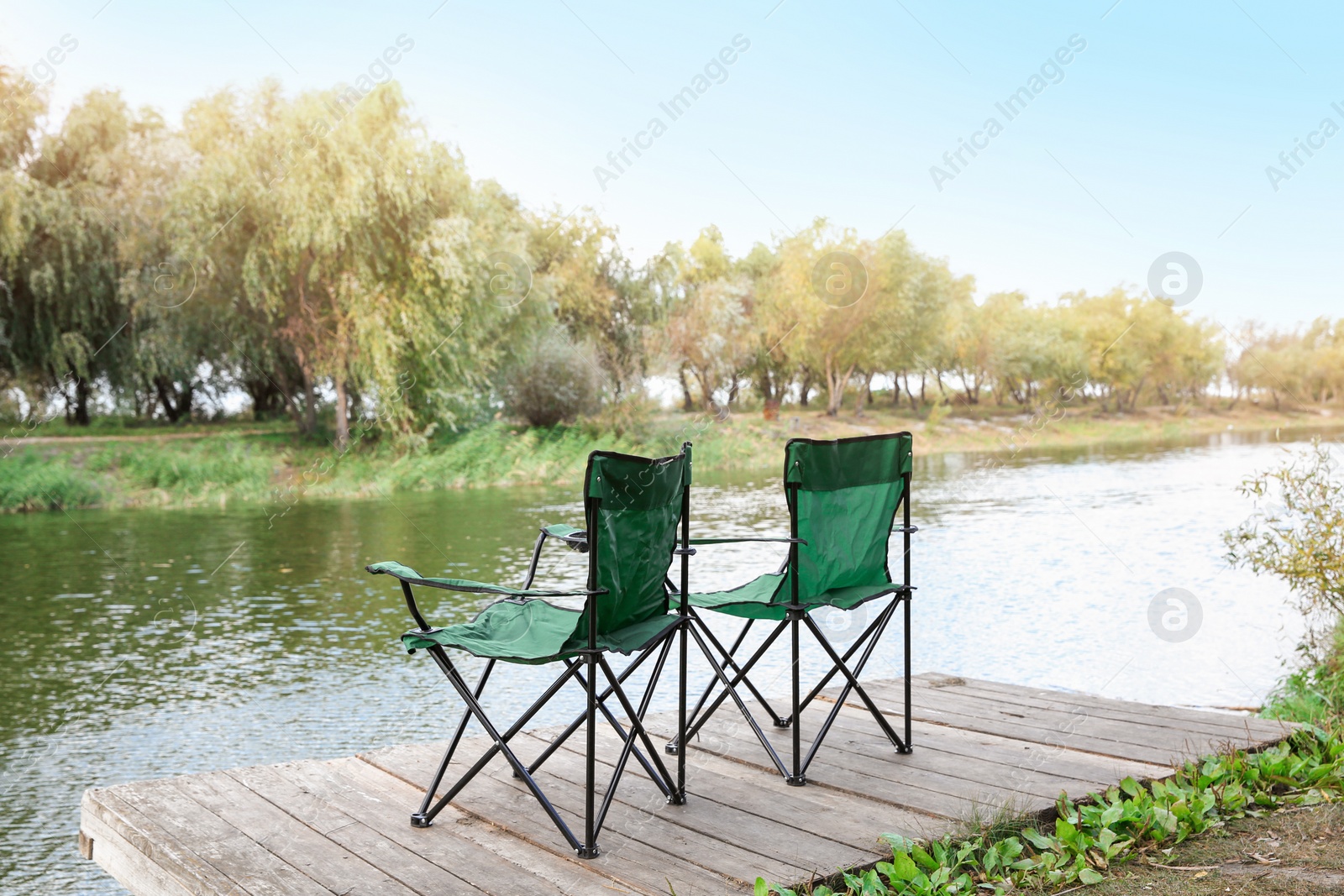 Photo of Fishing chairs on wooden pier near river