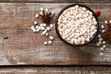 Photo of Tasty hot chocolate with marshmallows on wooden table, top view. Space for text