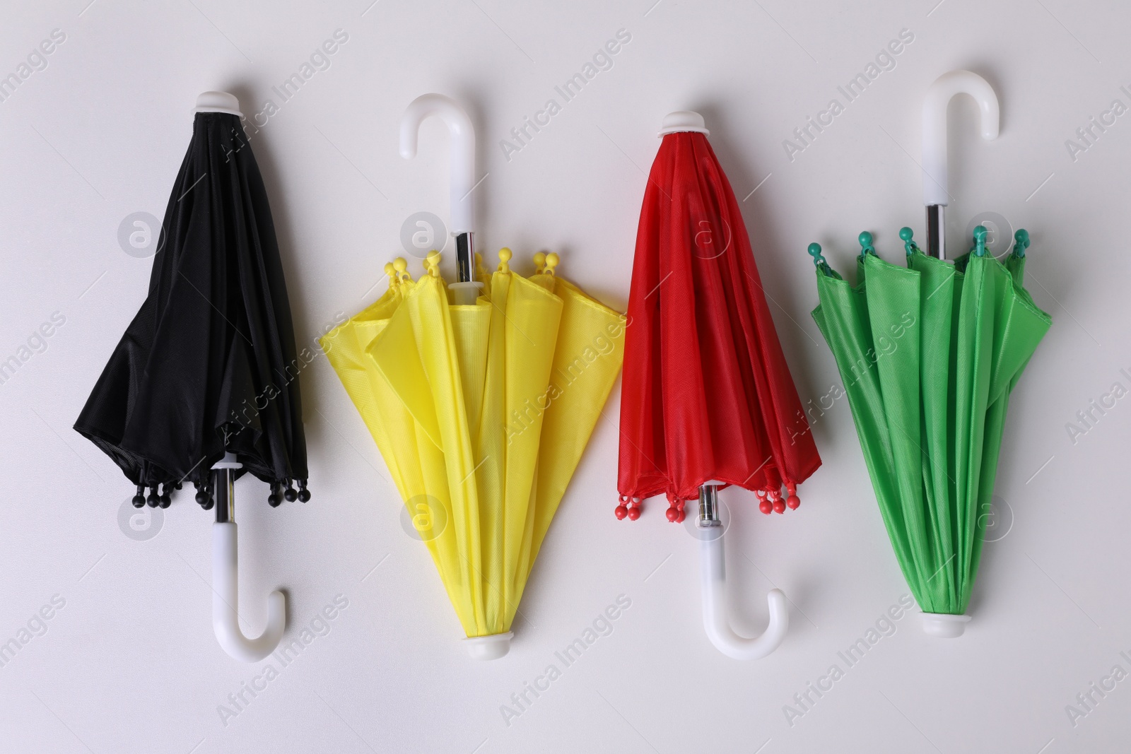 Photo of Small color umbrellas on white background, top view