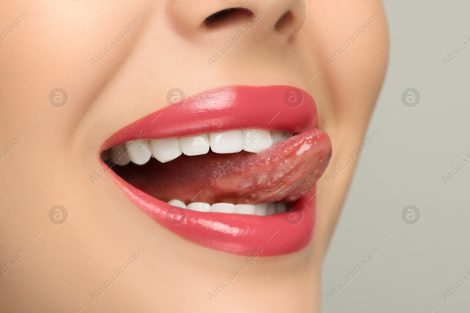 Photo of Woman showing her tongue on light background, closeup