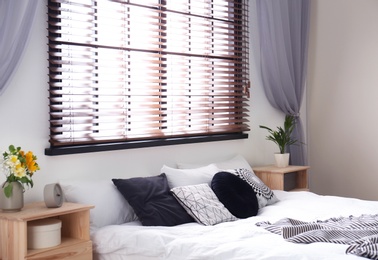 Modern room interior with comfortable double bed and window blinds