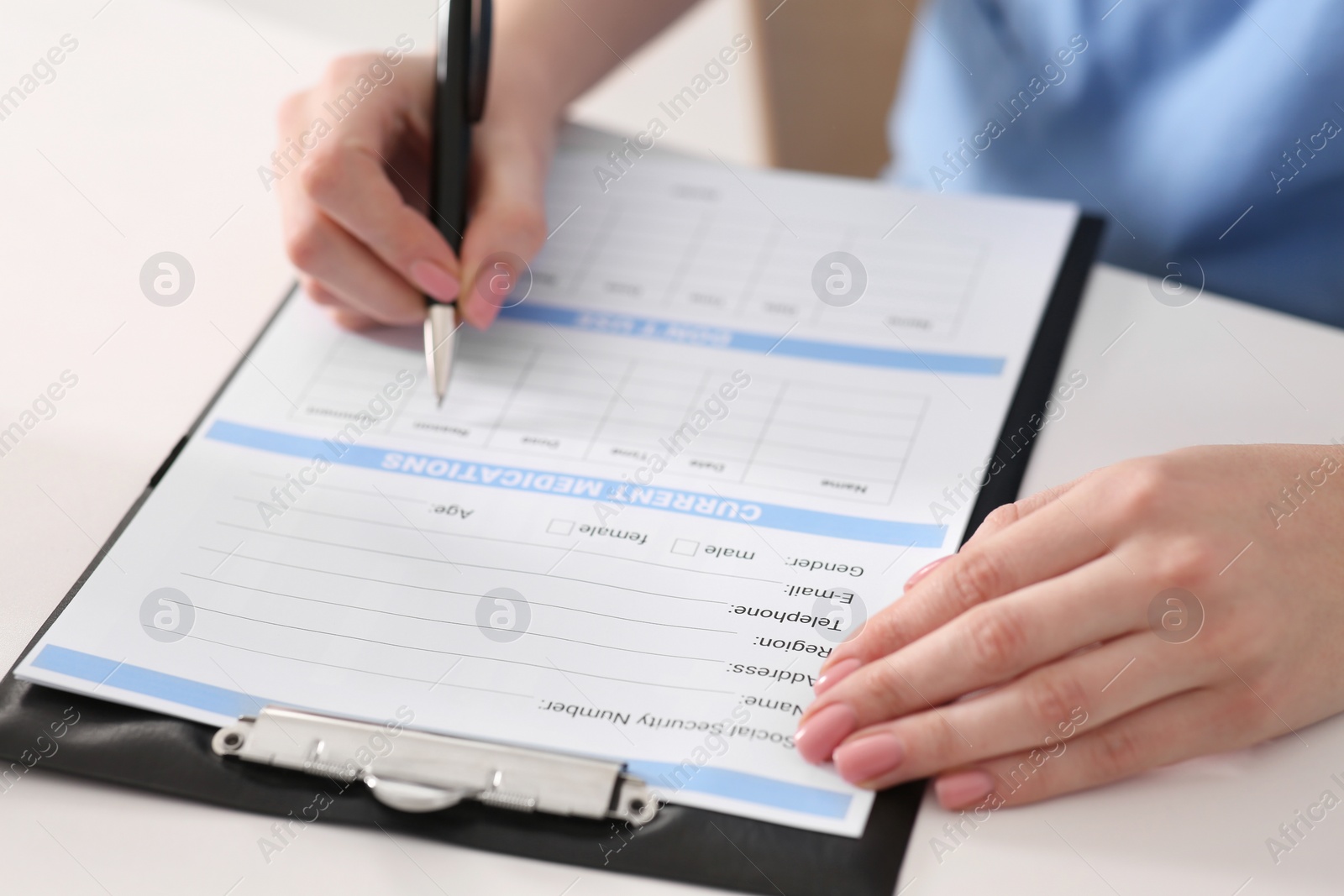 Photo of Doctor filling patient's medical card at table in clinic, closeup