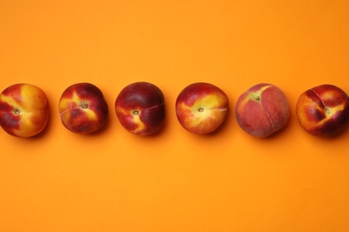 Photo of Flat lay composition with ripe peaches on orange background, space for text