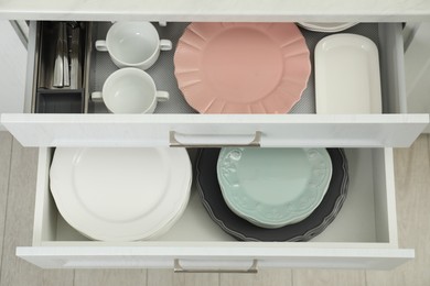 Photo of Clean plates, bowls and cutlery in drawers indoors, top view