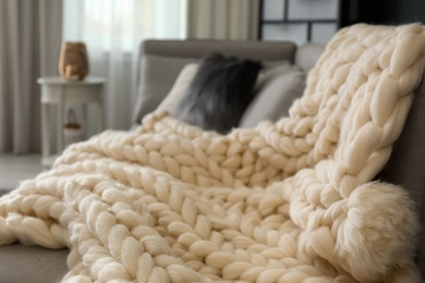 White knitted plaid on sofa in living room. Interior design