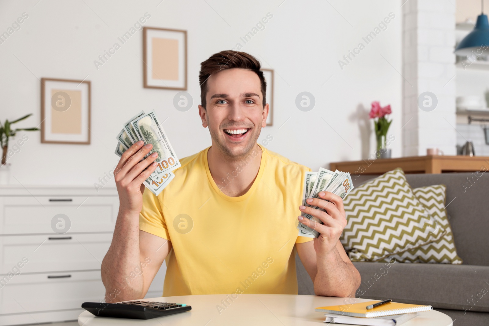 Photo of Happy man with money at table in living room