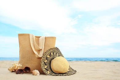 Photo of Different stylish beach objects, coral and seashell on sand near sea. Space for text