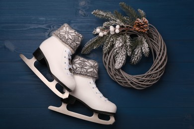 Pair of ice skates with Christmas decor on blue wooden background, flat lay