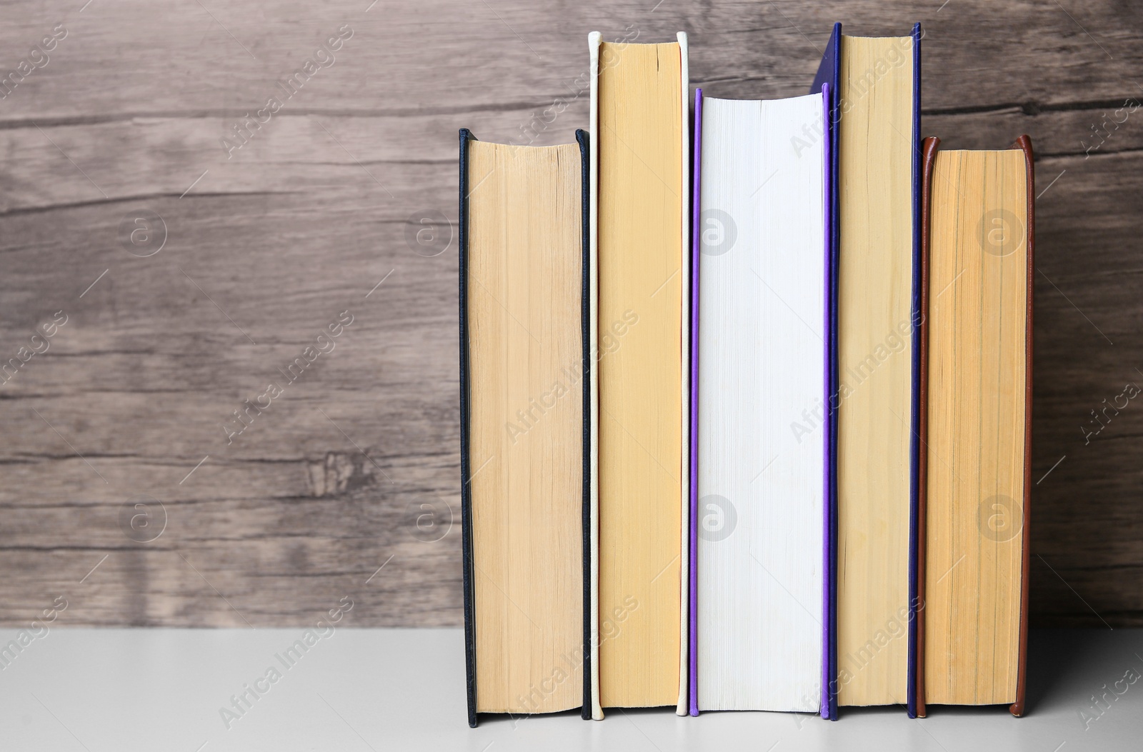 Photo of Collection of different books on white shelf, space for text