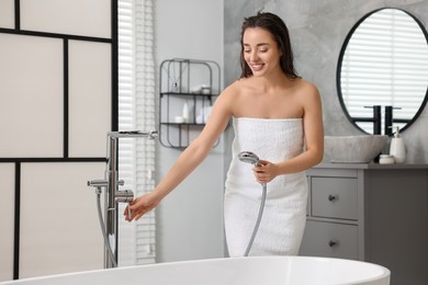 Photo of Smiling woman turning off water after shower in bathroom