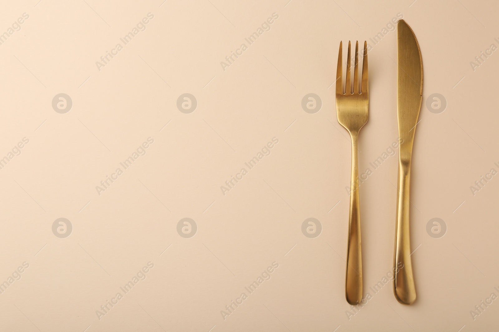 Photo of Stylish cutlery on beige table, top view. Space for text