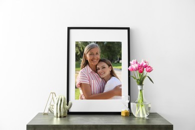 Image of Family portrait of mother and daughter in photo frame on table near white wall