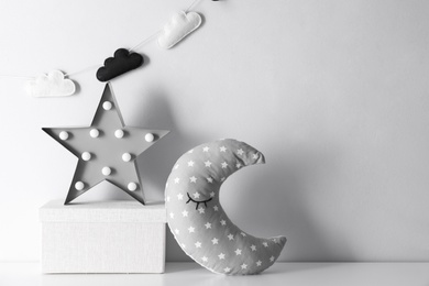 Photo of Star shaped lamp, toy moon and box on table, space for text. Interior design