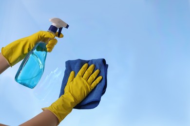 Photo of Woman cleaning window glass with rag and detergent, closeup. Space for text