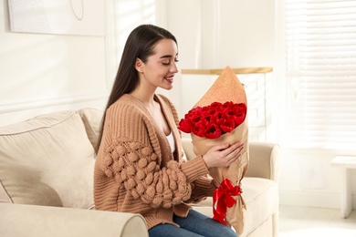 Photo of Happy woman with red tulip bouquet at home. 8th of March celebration