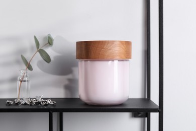 Jar of hand cream, jewelry and eucalyptus branch on shelf