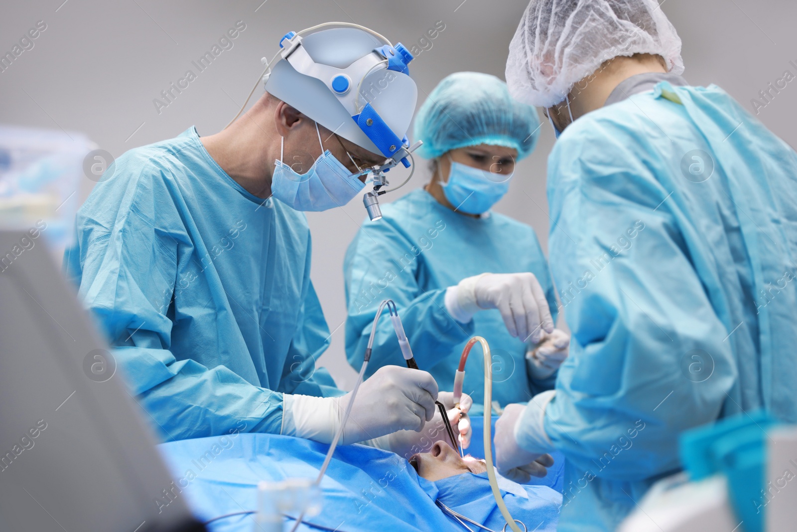 Photo of Professional doctors performing 
frontal sinus trephination in surgery room