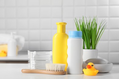 Baby cosmetic products, bath duck, brush and cotton swabs on white table. Space for text