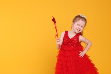 Photo of Cute girl in red dress with diadem and magic wand on yellow background, space for text. Little princess