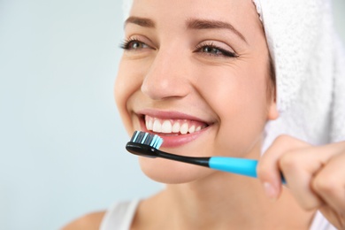 Young woman with toothbrush on blurred background, closeup