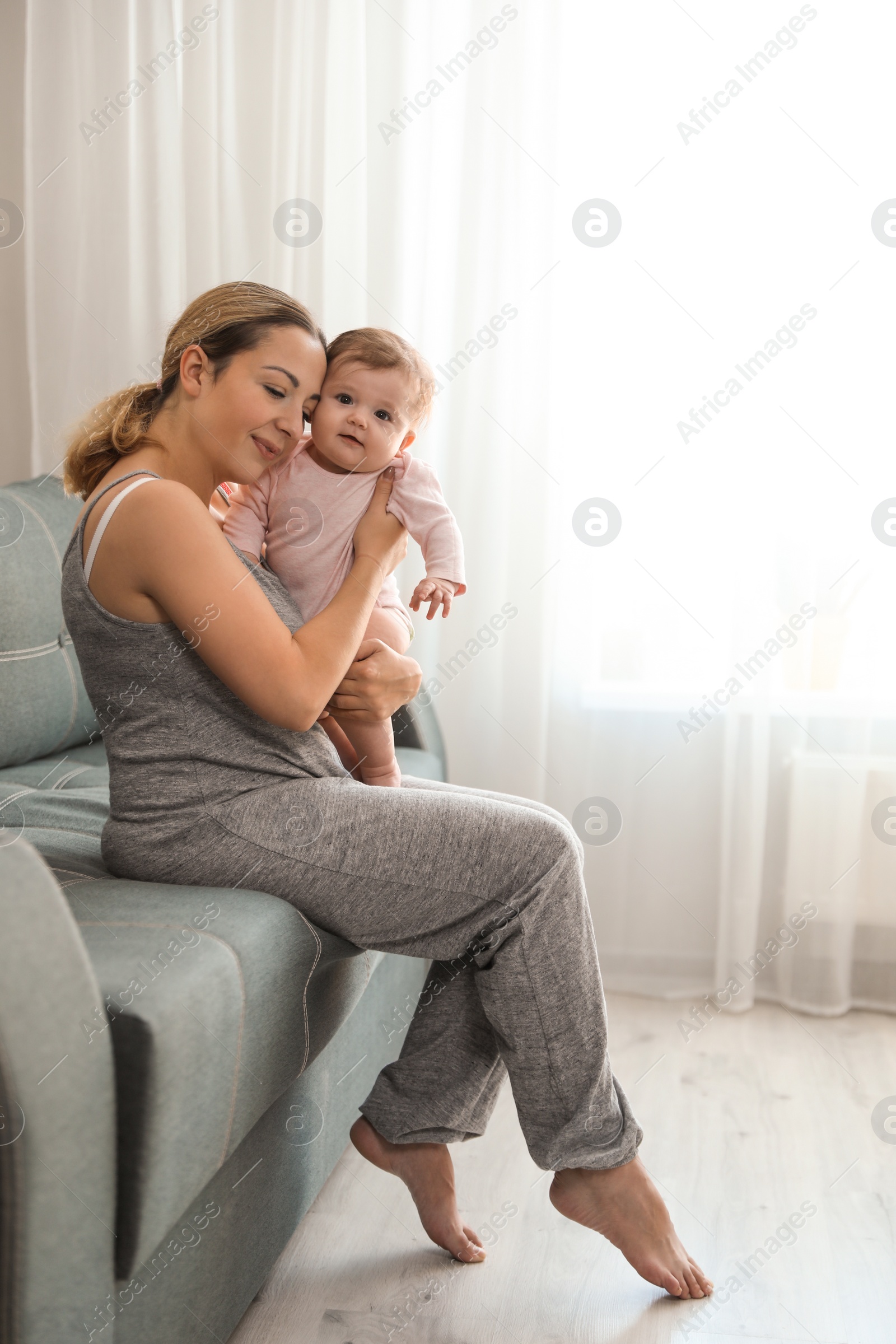 Photo of Young woman with her cute baby at home