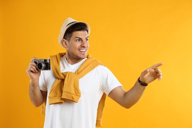 Male tourist with camera on yellow background