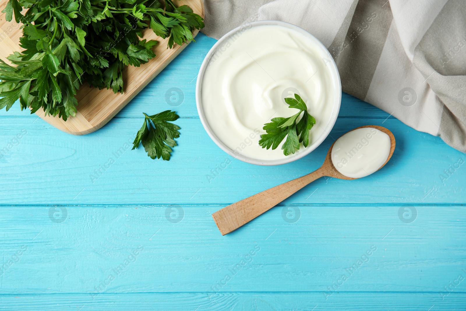 Photo of Flat lay composition with sour cream and parsley on light blue wooden table, space for text