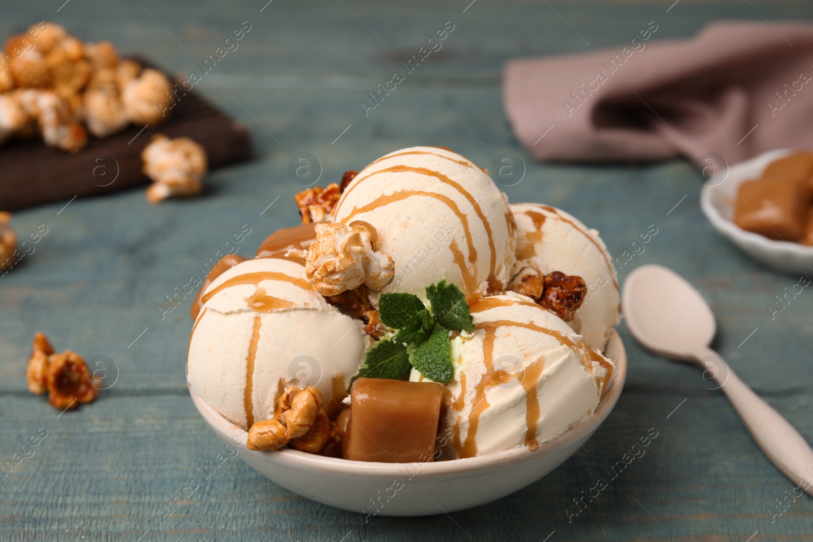 Photo of Delicious ice cream with caramel, popcorn and sauce served on table