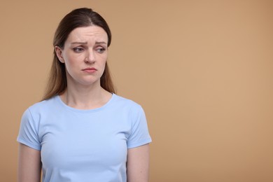 Photo of Portrait of sad woman on beige background, space for text