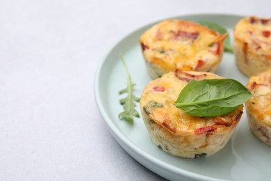 Photo of Freshly baked bacon and egg muffins with cheese on light gray table, closeup. Space for text