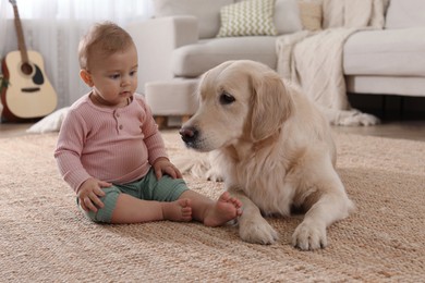 Cute little baby with adorable dog on floor at home