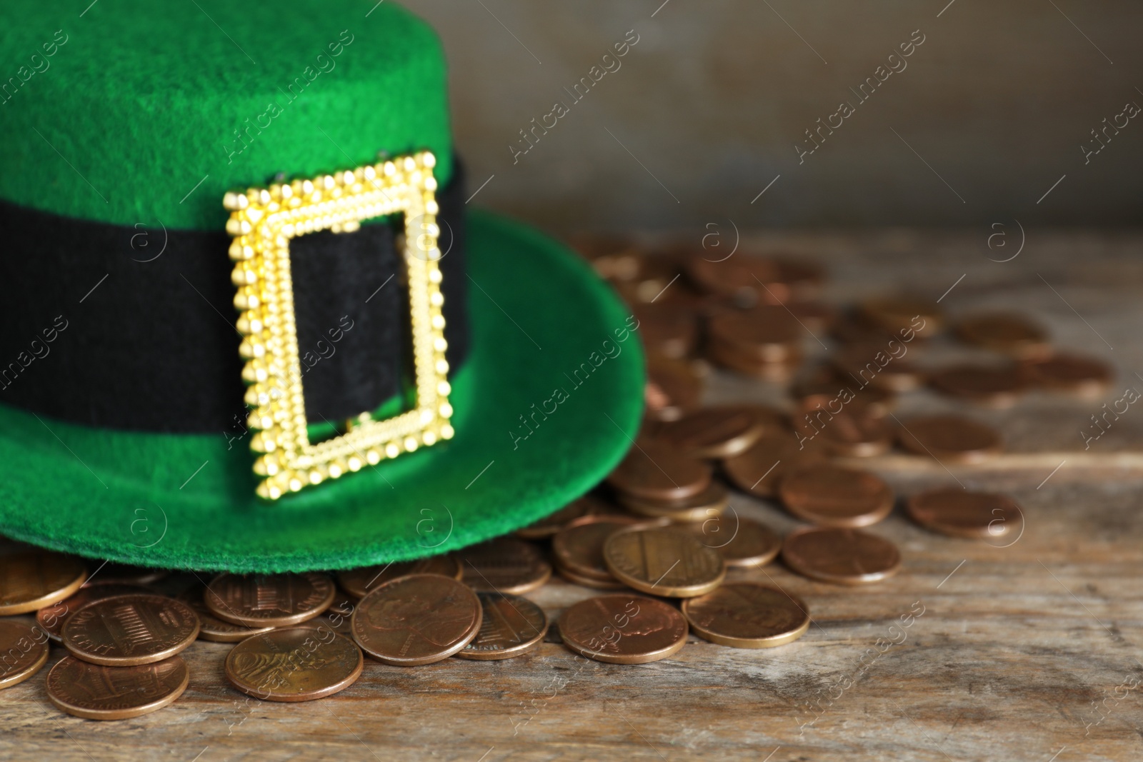 Photo of Green leprechaun hat and gold coins on wooden table, space for text. St. Patrick's Day celebration