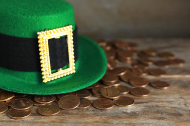 Green leprechaun hat and gold coins on wooden table, space for text. St. Patrick's Day celebration