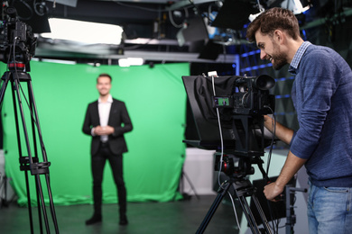 Photo of Presenter and video camera operator working in studio. News broadcasting